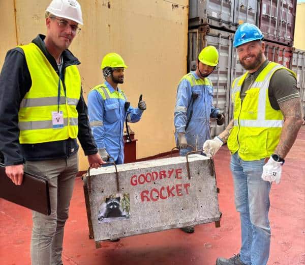 Four men on board a ship carrying a transport crate