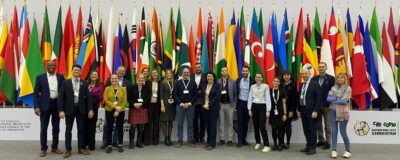 Group of people standing before flags.