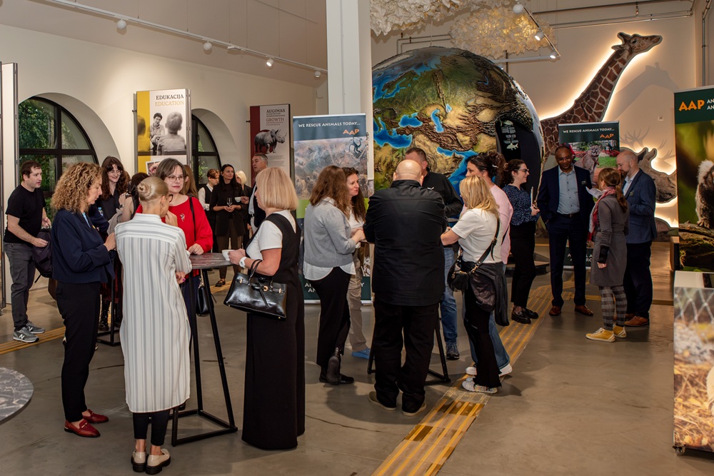 Group of people standing around tables with a large globe in the background.